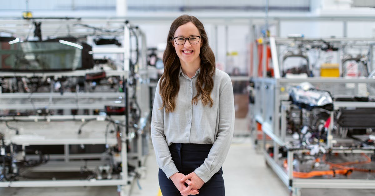 Smiling woman engineer standing confidently in a modern industrial workshop setting.